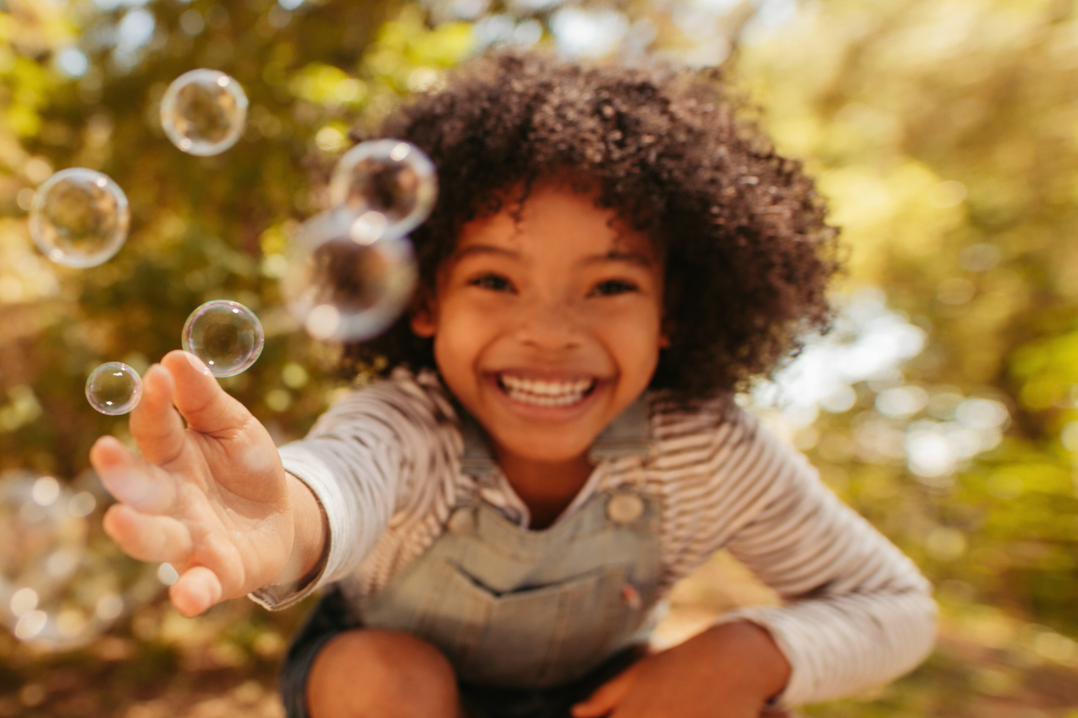 A child, laughing, with bubbles, out of doors