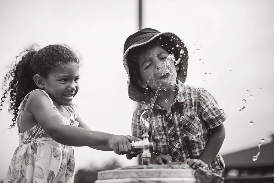 Girl pressing water fountain for her friend