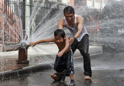 Father and son getting wet inthe water fountain