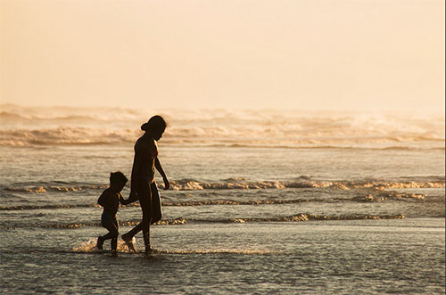 Mother and son on beach at sunset