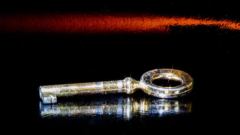 A golden key lying on a darkened table, glinting in the light